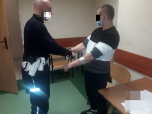 Policjant zakłada kajdanki zatrzymanemu