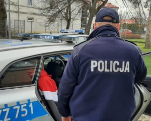 W radiowozie znajduje się zatrzymany mężczyzna, obok umundurowany policjant