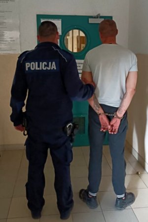 Umundurowany policjant doprowadza do aresztu zatrzymanego mężczyznę