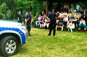 Umundurowani policjanci prowadza zajęcia dla uczniów w plenerze