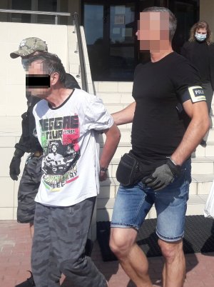 Mężczyzna doprowadzany przez policjantów do sadu