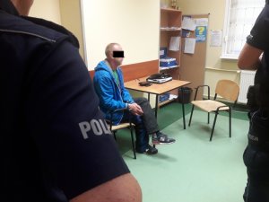 Zatrzymany kierowca w pomieszczeniu komendy. Obok umundurowani policjanci