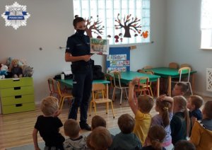 Dzieci w sali z policjantem odpowiadają na pytania gdzie można bezpiecznie się bawić