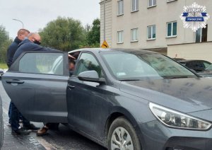 Policjanci z zatrzymanym mężczyzną przy wsiadaniu do radiowozu