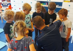 Policjant w sali pokazujący dzieciom kajdanki