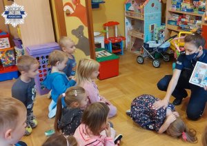 Policjantka pokazuje dzieciom jaką pozycję należy przyjąć przy spotkaniu z groźnym zwierzęciem