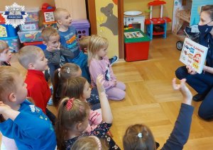 Dzieci w sali z policjantką przypominają sobie numery alarmowe