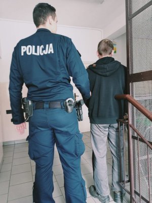 Umundurowany policjant przeprowadza zatrzymanego