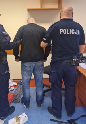 W pomieszczeniu umundurowani funkcjonariusze wraz z zatrzymanym