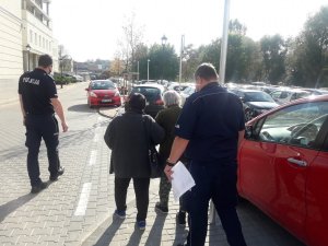 Umundurowani policjanci odprowadzają wraz z opiekunką  83- letnią kobietę