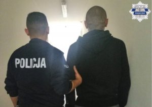 Policjant prowadzi zatrzymanego mężczyznę