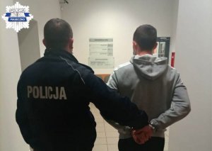 Policjant prowadzi zatrzymanego przez korytarz komisariatu