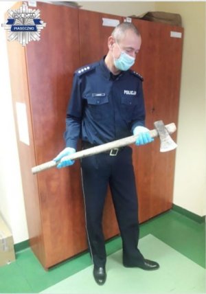 Umundurowany policjant trzymający zabezpieczoną siekierę