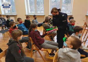 Policjantka przekazuje dzieciom opaski odblaskowe