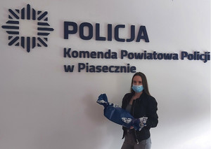 zdjęcie nastolatki w sali konferencyjnej Komendy Powiatowej Policji w Piasecznie wraz z otrzymanym pamiątkowym prezentem