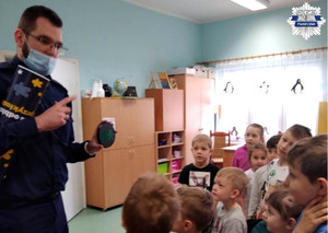 Policjant rozmawia z dziećmi o noszeniu elementów odblaskowych