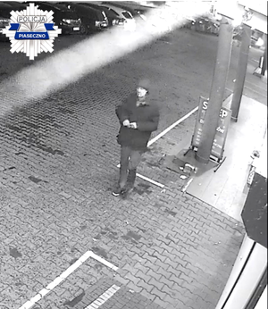 Mężczyzna w ciemnej kurtce obok sklepu