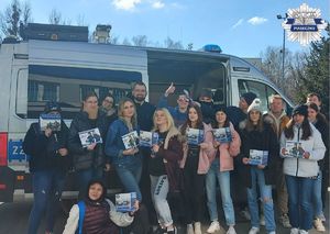 Zdjęcie policjanta wraz z uczniami na tle radiowozu