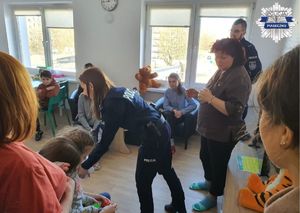 Policjantka przekazuje elementy odblaskowe wszystkim uczestnikom spotkania