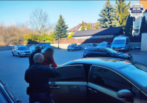 Policjanci z zatrzymanym mężczyzną podczas wsiadania do samochodu służbowego