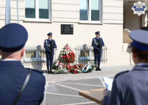 Policjanci z kompanii reprezentacyjnej Komendy Stołecznej Policji stoją przy tablicy upamiętniającej poległego policjanta