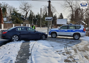 Na zdjęciu radiowóz zaparkowany na poboczu oraz kontrolowany samochód, a przy nim policjant