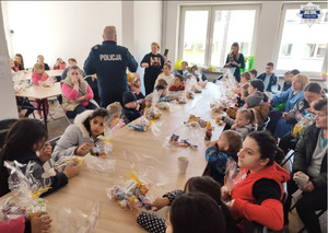 Policjanci przekazują dzieciom prezenty w ośrodku dla uchodzców, dzieci siedza przy stolikach