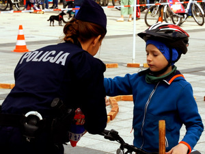 Policjantka nagradza chłopca który pokonał tor przeszkód słodkimi nagrodami - lizakami oraz odblaskowymi zawieszkami