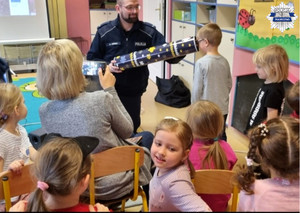 Policjant pokazuje dzieciom widoczność pieszych w odblaskach przy użyciu magicznej tuby