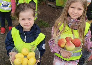 Dzieci biorące udział w akcji, dwie dziewczynki. Jedna trzyma jabłka, druga cytryny