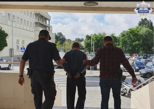 Policjanci wychodzący z komendy wraz z zatrzymanym mężczyzną