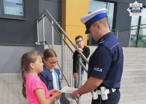 Dzieci wręczają policjantowi podziękowanie ze spotkanie