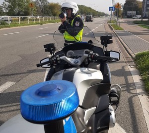 Policjant dokonujący pomiaru prędkości, w tle również motocykl policyjny