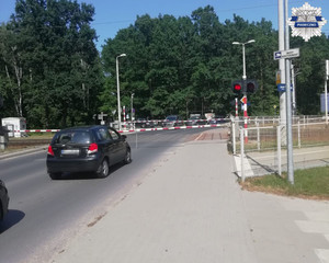 Opuszczone zapory kolejowy, światło czerwone na sygnalizatorze, samochody stoją po dwóch stronach zapór