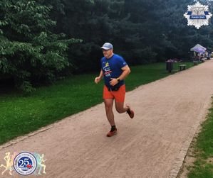 Policjant w stroju sportowym biegnący po ścieżce biegowej sam.