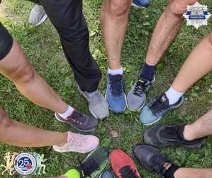 W okręgu stoją osoby, u których widać tylko jedna nogę i but.