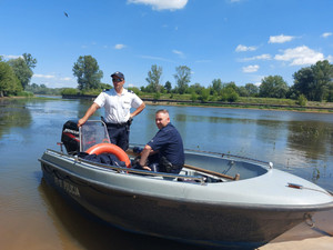 Na rzece jest łódź motorowa policyjna w której jest umundurowany policjant z policji rzecznej oraz umundurowany dzielnicowy.