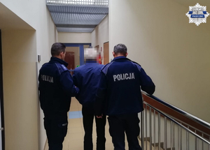 Policjanci dzielnicowi wraz z zatrzymanym mężczyzną na korytarzu jednostki policji
