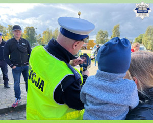 Policjant pokazuje dziecku sprzęt jakim dysponuje policja