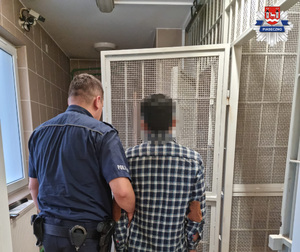 Umundurowany policjant z zatrzymanym mężczyzną