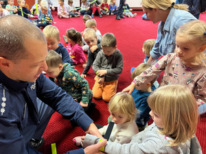 Policjant zakłada dzieciom opaski odblaskowe