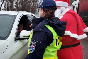 Policjantka w towarzystwie mikołaja daje kierowcy odblask