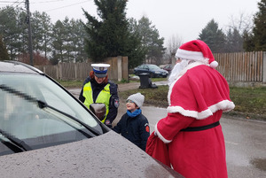Mikołaj wraz z policjantką i przedszkolakiem daje kierowcy prezent