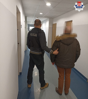 nieumundurowany policjant z zatrzymanym mężczyzną na korytarzu w budynku komendy