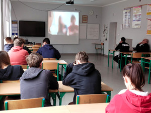 uczniowie siedzą w ławkach, wyświetlany jest film