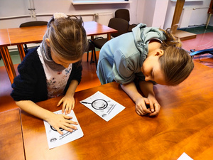 Na zdjęciu są dwie dziewczynki, jedna z nich robi odcisk dłoni na kartce papieru