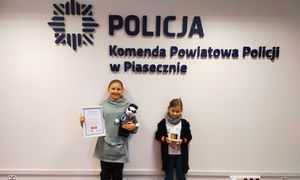 dziewczynki na tle napisu Komenda Powiatowa Policji w Piasecznie