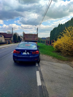 nieoznakowany radiowóz z wyświetlonym na tablicy napisem &quot;Policja&quot; oraz stojący przed nim samochód ciężarowy