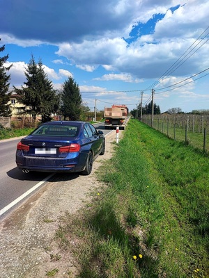 nieoznakowany radiowóz z wyświetlonym na tablicy napisem &quot;Policja&quot; oraz stojący przed nim samochód ciężarowy