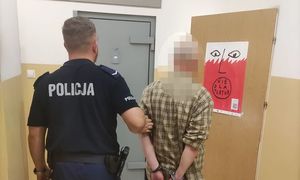 mężczyzna w asyście umundurowanego policjanta, stoją tyłem